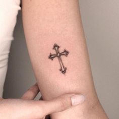 a cross tattoo on the arm of a woman