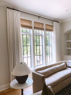 a living room filled with furniture and lots of white curtains on the window sill