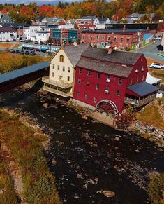 an aerial view of a red building in the middle of a river with fall foliage surrounding it