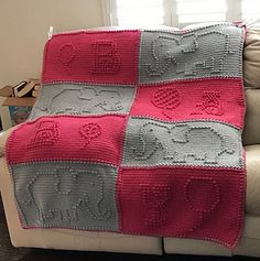 a crocheted blanket sitting on top of a couch in front of a window