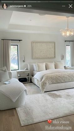 a large white bedroom with two windows and a chandelier hanging from the ceiling