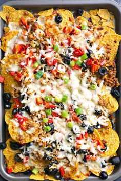 nachos topped with cheese, black olives and ground beef in a pan