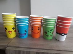 there are many different colored cups with faces on them, all lined up in a row