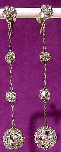 DO NOT PURCHASE. Both earrings missing from inventory, but not sold.  A pair of Art Deco rhinestone dangly ball earrings circa 1920s. This flashy pair of screw back earrings are gilt brass-mounted. They measure 2-1/2" in length and these elegant earrings feature two small rhinestone balls and a 3/8" across large rhinestone ball all linked with fine chain; all stones are claw-set and they swing freely. This pair is in excellent original condition with no chips, cracks, dents, bends, corrosion, lo Festive Gold Earrings With Rhinestones, Festive Gold Rhinestone Earrings, Antique Gold Jeweled Earrings, Gold Rhinestone Earrings For Festive Occasions, Antique Gold Jewelry With Rhinestones, Victorian Gold Jewelry With Rhinestones, Victorian Jeweled Gold Earrings, Victorian Style Gold Clip-on Earrings For Party, Antique Gold Clip-on Earrings For Party