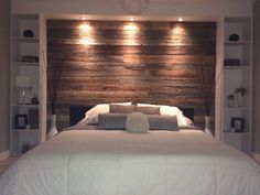 a large bed sitting in a bedroom next to a wooden headboard with lights on it