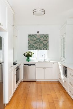 a clean kitchen with white cabinets and wood floors is pictured in this image from the front view