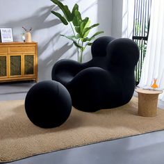 two black chairs sitting on top of a rug next to a plant in a living room