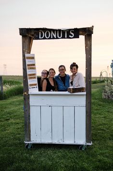 three women are standing in front of a sign that says donuts on the side