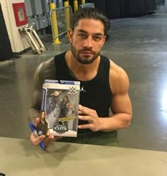 a man sitting on the floor holding up a box with an action figure in it