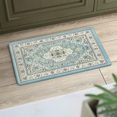 a blue rug on the floor in front of a cabinet and potted green plant