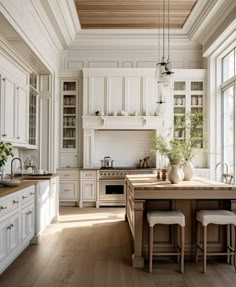 a large kitchen with white cabinets and wooden flooring, along with an island in the middle