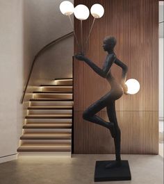 a statue is standing in front of a staircase and some lights on the wall behind it