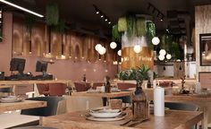 the interior of a restaurant with tables, chairs and potted plants hanging from the ceiling