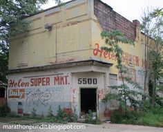 an old run down building with graffiti on it's side and trees in the foreground