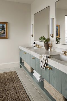 a bathroom with two sinks, mirrors and rugs on the floor in front of it