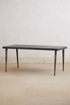 a black table sitting on top of a floor next to a white wall in an empty room