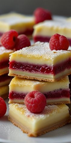 raspberry cheesecake bars stacked on top of each other with fresh raspberries