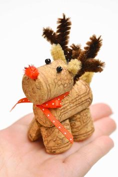 a hand holding a small stuffed animal with red ribbon on it's head and nose