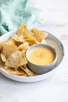 a white bowl filled with chips and dipping sauce