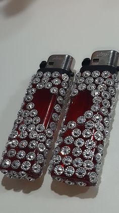 two red lighters with diamonds on them sitting next to each other in front of a white table