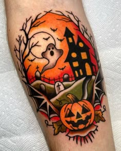 a halloween themed tattoo with a house, pumpkins and bats on the leg area