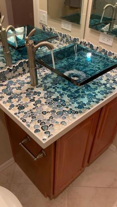 a bathroom sink with blue and white tiles on the counter top next to a mirror