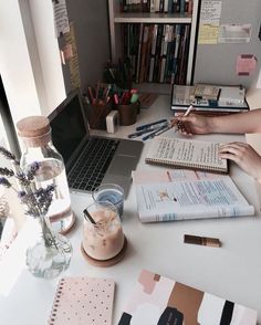 someone is working at their desk with many books and notebooks on the table in front of them