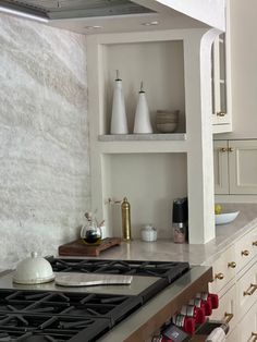 a stove top oven sitting inside of a kitchen next to white cabinets and counter tops