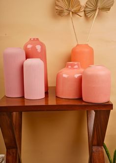 pink and orange vases are sitting on a wooden table next to a cactus plant