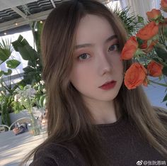 a woman with long brown hair and orange flowers in her hair is looking at the camera