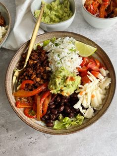 a bowl filled with rice, black beans and vegetables next to bowls of guacamole