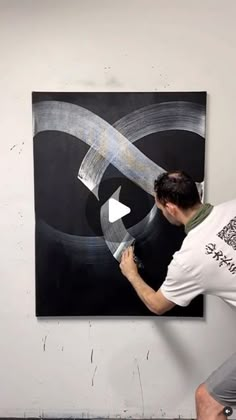 a man is painting an abstract black and white artwork