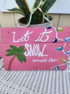 a wooden sign that says let it snow somewhere else with a palm tree on it