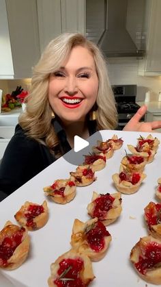 a woman is holding up a tray with small appetizers on it and pointing to the camera