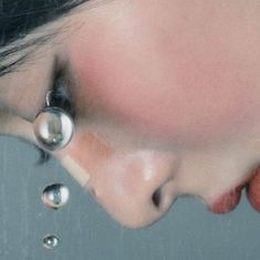 a woman's face is reflected in a mirror with drops of water on it