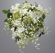 a bouquet of white flowers and green leaves on a gray background with space for text