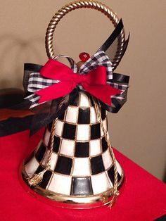 a black and white checkerboard bell with a red bow on the top is sitting on a table