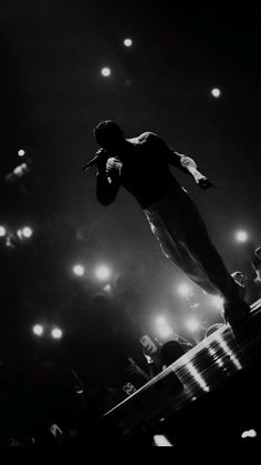 a man standing on top of a stage with his hands in his pockets as he sings