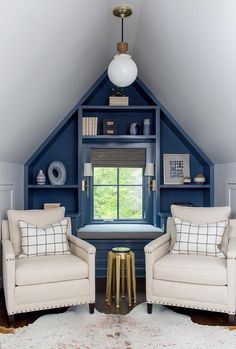 two chairs and a table in front of a blue book shelf with books on it