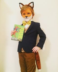 a young boy dressed up as a fox with a book in his hand and wearing a suit