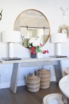 a table with flowers in a vase and two baskets on the floor next to it