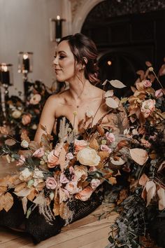 a woman is sitting on the floor with flowers in her hair and wearing a black dress