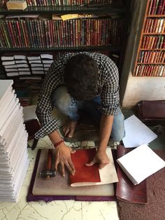 a man is working on a piece of paper in front of a bookcase full of books