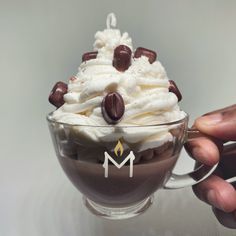 a person holding a cup filled with whipped cream and chocolate chips