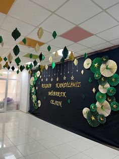 an office decorated with green and gold paper fans hanging from the ceiling, in front of a black wall