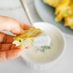 a person holding up food in front of a plate with eggs and sauce on it