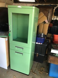 a green cabinet sitting in the middle of a room next to other boxes and containers