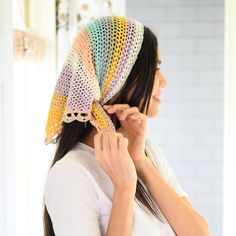 a woman wearing a multicolored crocheted head scarf on top of her head