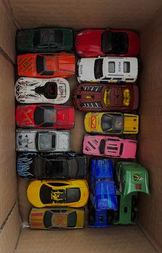 a cardboard box filled with lots of different colored toy cars in it's storage compartment