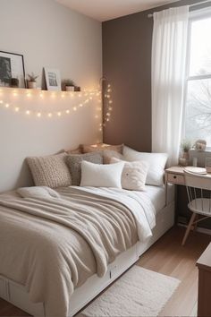 a small bedroom with a bed, desk and lights on the wall above it's headboard